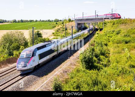 Ein TGV inOui und ein Thalys-Hochgeschwindigkeitszug fahren an einem sonnigen Tag übereinander auf dem Land. Stockfoto