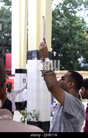 16. Juli 2022, Dhaka, Dhaka, Bangladesch: Mohiuddin Roni, Eine Studentin der Dhaka University ist seit 10 Tagen im Bahnhof Kamalapur in Dhaka, um gegen die schwarze Vermarktung von Bahntickets und das allgemeine Missmanagement zu protestieren. Während Eid UL-Adha, auf dem Rückweg nach Hause, buchte er das Zugticket über das Internet, konnte aber wegen des Schwarzmarktproblems mit dem Ticket nicht reisen. Dann nahm er einen Proteststand auf dem Bahnhof und begann, durch darstellende Künste zu protestieren. Er selbst hat seine Hände angekettet. Er stellte 6-Punkte-Forderungen vor und kündigte an, sein Sit-in-Programm so lange fortzusetzen, bis es soweit ist Stockfoto