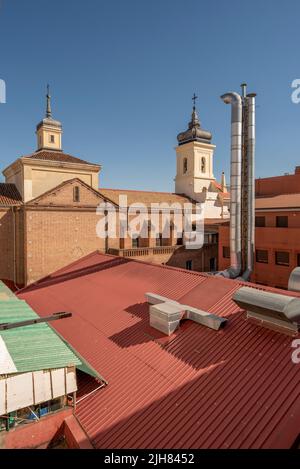 Innenfassaden mit roten Metalldächern, Edelstahlschornsteinen und Türmen einer alten Kirche Stockfoto