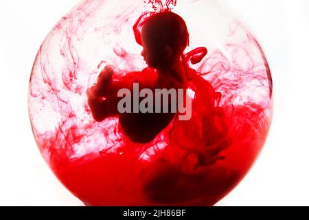 Abtreibungskonzept. Babypuppe im roten Blut sieht aus wie eine Abtreibung. Stockfoto