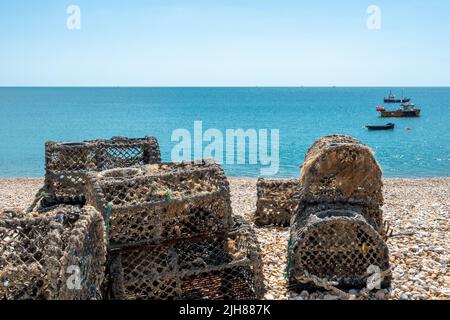 Hummertöpfe fallen am einsamen Strand von Selsey West Sussex England mit dem Meer und Fischerbooten im Hintergrund Stockfoto