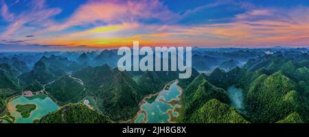 Eine Luftaufnahme der von einem Fluss umgebenen Berge bei Sonnenuntergang im Yangshuo County, China Stockfoto