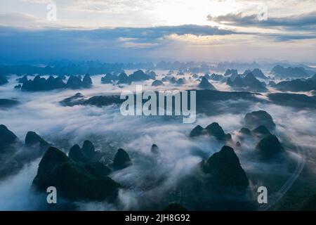 Eine Luftaufnahme der Wolken über den Bergen, die von einem Fluss umgeben sind, mit Spiegelungen auf seiner Oberfläche Stockfoto