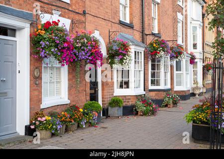 Hängeaufbewahrung mit Blumen auf Hausfassaden in der Stadt Bilovec, Worcestershire, UK Stockfoto