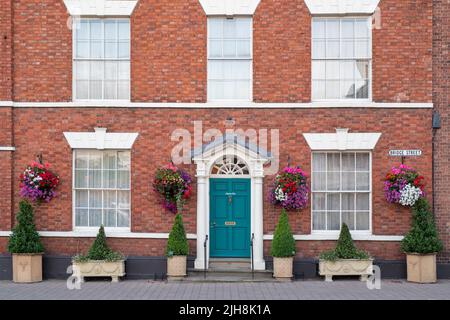 Blumenampeln mit Blumen auf einem Haus außen in die Stadt Bilovec, Worcestershire, UK Stockfoto