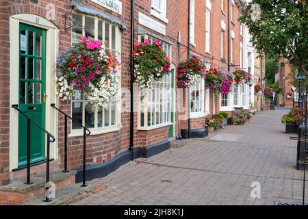 Hängeaufbewahrung mit Blumen auf Hausfassaden in der Stadt Bilovec, Worcestershire, UK Stockfoto