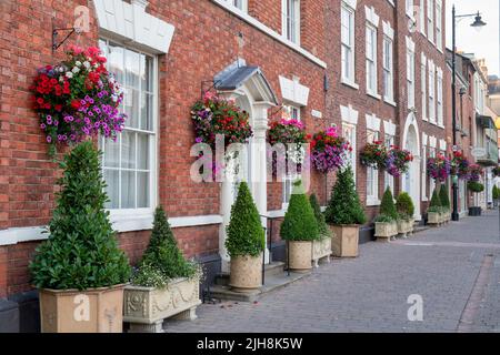 Hängeaufbewahrung mit Blumen auf Hausfassaden in der Stadt Bilovec, Worcestershire, UK Stockfoto