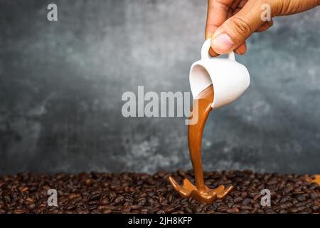 Ein Mann verschüttet Espresso auf Kaffeebohnen aus einer Miniatur-Tasse Stockfoto