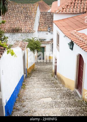 Die Stadt Óbidos, Portugal: Steile Gasse zwischen alten weißen Häusern. Stockfoto