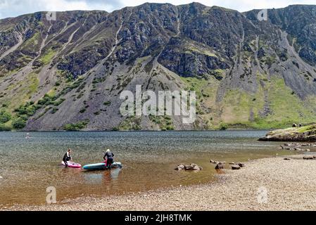 Paddelboarder am Wastwater Lake mit den dramatischen Geröllhängen im Hintergrund, an einem Sommertag Wasdale, Cumbria England Stockfoto