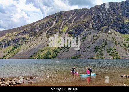 Paddelboarder am Wastwater Lake mit den dramatischen Geröllhängen im Hintergrund, an einem Sommertag Wasdale, Cumbria England Stockfoto