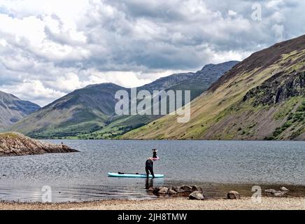 Paddelboarder am Wastwater Lake mit den dramatischen Geröllhängen im Hintergrund, an einem Sommertag Wasdale, Cumbria England Stockfoto