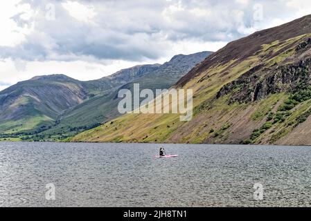 Paddelboarder am Wastwater Lake mit den dramatischen Geröllhängen im Hintergrund, an einem Sommertag Wasdale, Cumbria England Stockfoto