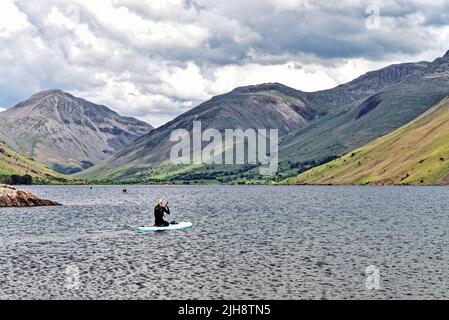 Paddelboarder am Wastwater Lake mit den dramatischen Geröllhängen im Hintergrund, an einem Sommertag Wasdale, Cumbria England Stockfoto