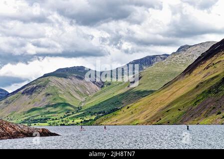 Paddelboarder am Wastwater Lake mit den dramatischen Geröllhängen im Hintergrund, an einem Sommertag Wasdale, Cumbria England Stockfoto