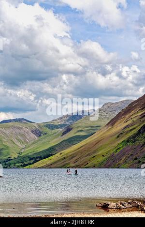 Paddelboarder am Wastwater Lake mit den dramatischen Geröllhängen im Hintergrund, an einem Sommertag Wasdale, Cumbria England Stockfoto