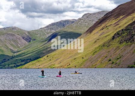 Paddelboarder am Wastwater Lake mit den dramatischen Geröllhängen im Hintergrund, an einem Sommertag Wasdale, Cumbria England Stockfoto