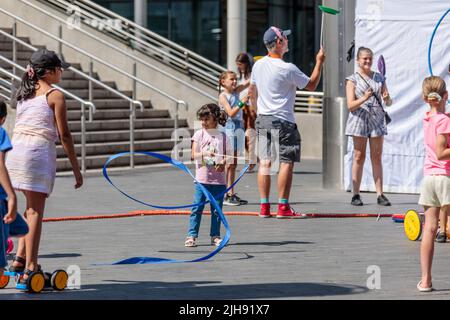 Wembley Park, London, Großbritannien. 16.. Juli 2022. Familien lernen beim Zirkus-Skills-Workshop, wenn der International Busking Day wieder im Wembley Park ist. Das kostenlose, ganztägige Festival hat große Namen, die sich auf 9 Bühnen mit aufstrebenden Künstlern und Basiskünstlern teilen. Die Veranstaltung im Wembley Park umfasst auch Bereiche für Familienspaß mit Zirkusworkshops, Magie- und Comedy-Acts, Eskapologenroutine, Gesichtsbemalung und Ballonkünstler. Der internationale Bucking Day, der vom Bürgermeister von London unterstützt wird, wird von Busk in London präsentiert. Amanda Rose/Alamy Live News Stockfoto