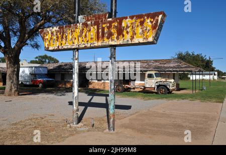 In der Nähe eines alten Lastwagens im ehemaligen Elm Motel in der kleinen Stadt Erick, Oklahoma, an der Route 66, steht ein rostiges Schild mit der Aufschrift „angemessene Preise“. Stockfoto