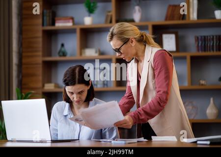 Verärgerte weibliche Chefin schimpft verängstigte Büroangestellte. Der anspruchsvolle Manager ist über Faulheit und Fehler bei der Arbeit des Mitarbeiters verärgert. Autoritär Stockfoto