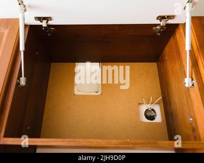 Installation einer Küchenhaube, Renovierung in einem neuen Haus, ein Loch mit Steckdosendrähten für die Haubenverbindung. Stockfoto