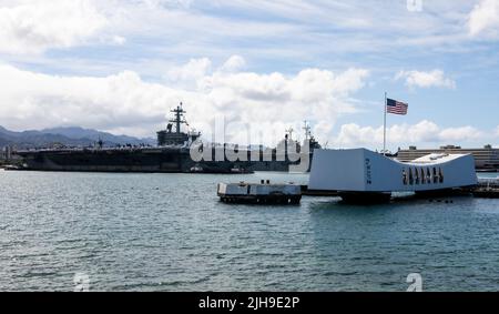 220628-N-XX566-1077 PEARL HARBOR (28. Juni 2022) – der Flugzeugträger USS Abraham Lincoln (CVN 72) der Nimitz-Klasse ehrt das USS Arizona Memorial, als das Schiff an der Joint Base Pearl Harbor-Hickam ankommt, um an der RIMPAC 2022 teilzunehmen. 26 Nationen, 38 Schiffe, vier U-Boote, mehr als 170 Flugzeuge und 25.000 Mitarbeiter nehmen vom 29. Juni bis zum 4. August an RIMPAC in und um die Hawaii-Inseln und Südkalifornien Teil. RIMPAC, die weltweit größte internationale maritime Übung, bietet eine einzigartige Ausbildungsmöglichkeit und fördert und unterstützt die Zusammenarbeit Stockfoto