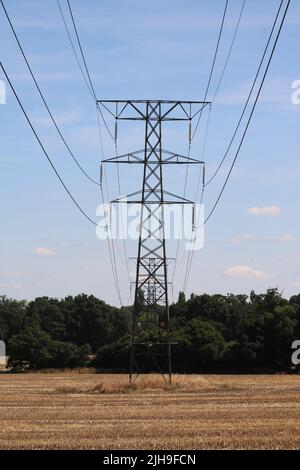 Strompylon gegen tiefblauen Himmel mit Maisstoppel im Vordergrund Stockfoto