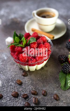 panna Cotta mit Himbeeren und einer Tasse Kaffee mit frischen Beeren. Stockfoto