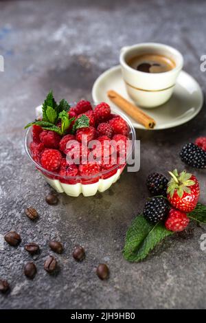 panna Cotta mit Himbeeren und einer Tasse Kaffee mit frischen Beeren. Stockfoto