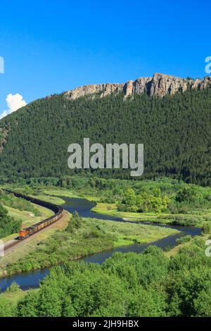 Trainieren Sie auf Eisenbahnschienen unter hohen Klippen entlang des clark Fork River Valley in der Nähe von drummond, montana Stockfoto