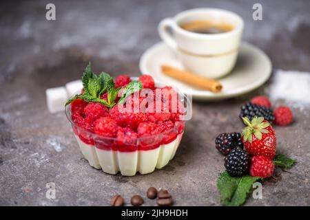 panna Cotta mit Himbeeren und einer Tasse Kaffee mit frischen Beeren. Stockfoto