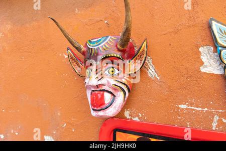 Traditioneller mexikanischer Karnevalstag des toten Dämons Teufel Orange Maske talavera typische Keramik zum Verkauf in einer Marktwand in Puebla City, Mexiko Stockfoto