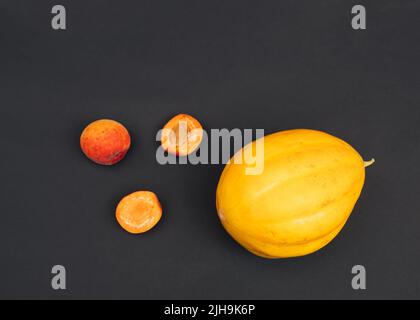 Kreatives Sommer-Layout aus frischen Aprikosen- und Melonenfrüchten auf dunklem Hintergrund. Flach liegend. Lebensmittelkonzept. Stockfoto