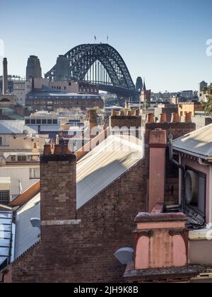 Die Sydney Harbour Bridge ragt über den Schornsteinfängeln von The Rocks, Sydneys ältestem Vorort. Stockfoto