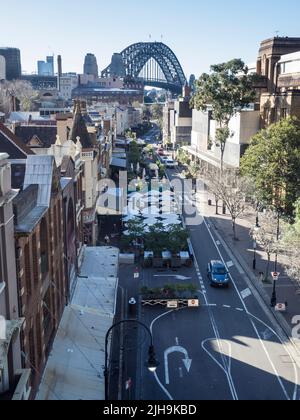 Die Sydney Harbour Bridge über der George St in The Rocks, Sydneys ältestem Vorort, steht vor der Kulisse. Stockfoto