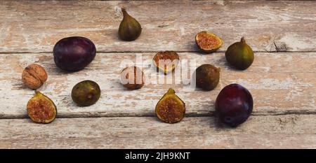 Close-up Vintage Komposition aus frischen reifen Feigen, Pflaumen und Nüssen auf altem Holztisch. Dunkler Hintergrund. Retro-Food-Konzept. Stockfoto