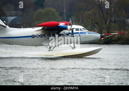 Das zweimotorige Wasserflugzeug ein Wasserflugzeug steigt aus dem Wasser, aus dem Waldsee, dem nördlichen Land auf. Wasserflugzeug Stockfoto