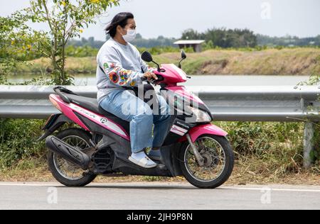 SAMUT PRAKAN, THAILAND, MAI 05 2022, Eine Frau mit Gesichtsmaske fährt ein Motorrad Stockfoto