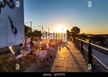 Personen, die bei Sonnenuntergang auf Liegestühlen sitzen, Paloma nad Wisłą im Museum für Moderne Kunst (Muzeum Sztuki Nowoczesnej w Warszawie), Powiśle, Warschau, Polen Stockfoto