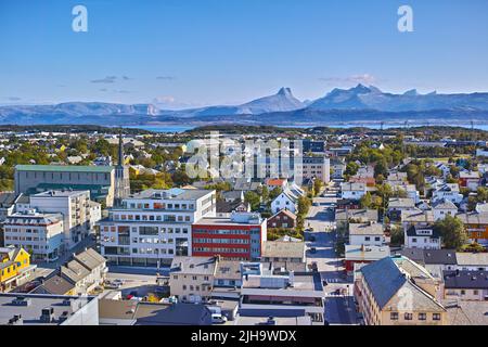 Luftaufnahme der Stadt Bodo in Norwegen an einem sonnigen Tag mit blauem Himmel. Szenische moderne Stadtlandschaft von Straßen und Gebäuden in der Nähe eines Berghorizonts mit Stockfoto