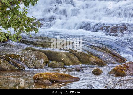 Bergbach und Wasserfall rauschen über Felsen und Felsbrocken. Schöne Naturlandschaft natürliche, frische Fluss fließt zwischen Bäumen in einem Öko Stockfoto