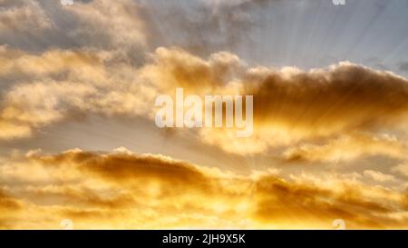 Sonnenstrahlen durchbrechen Eine goldfarbene Wolkenlandschaft Stockfoto