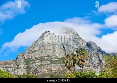 Lions Head Mountain mit wolkig blauem Himmel Kopieplatz. Wunderschöne Aussicht auf einen felsigen Berggipfel, der von viel üppiger grüner Vegetation bedeckt ist Stockfoto