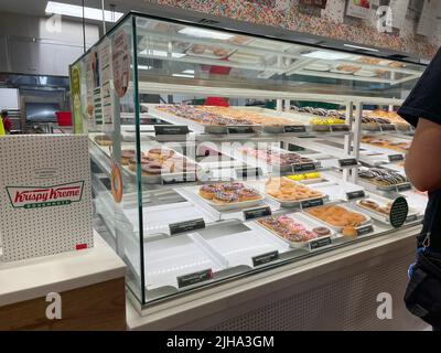 Im Inneren eines Krispy Kreme Donut-Ladens. Menschen in der Schlange, um Donuts zu kaufen. Stockfoto