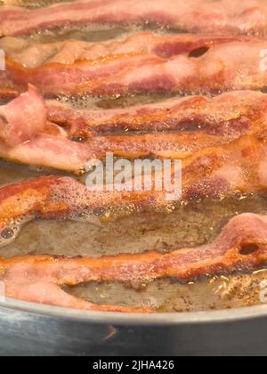 In Scheiben geschnittene Speckstreifen in einer Pfanne braten Stockfoto