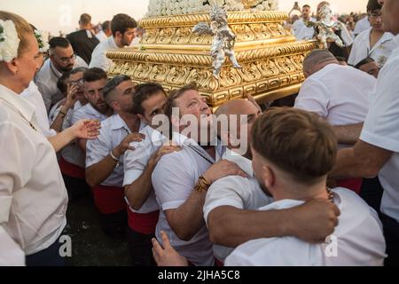 Malaga, Spanien. 17.. Juli 2022. Büßer der Bruderschaft Virgen del Carmen, die die Statue der Jungfrau Maria tragen, heiraten am Strand, während sie an der Prozession im Viertel El Palo teilnehmen. Jedes Jahr, am 16. Juli, feiert die Stadt Málaga ein religiöses Fest zu Ehren der Virgen del Carmen, der Schutzpatronin der Segler und Fischer. Die Statue der Jungfrau, die von einer Gruppe von Gläubigen in traditioneller Tracht entlang der Straßen getragen wird, wird auf einem Boot vom Strand aufgestellt, das später die Küste Malagas hinunter segelt. (Foto von Jesus Merida/SOPA Images/Sipa USA) Quelle: SIPA USA/Alamy Live News Stockfoto