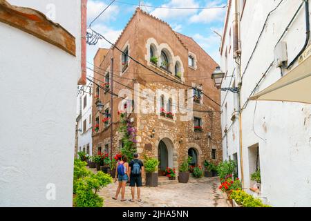 Ein Rucksacktouristen-Paar entscheidet sich für eine Gasse im mittelalterlichen historischen Dorf Tossa de Mar an der Costa Brava Küste von Katalonien Spanien. Stockfoto