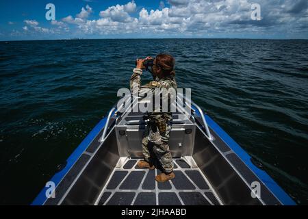 10. Juli 2022 - MacDill Air Force Base, Florida, USA - U.S. Air Force Airman 1. Class Samari Rivera-Rodriguez, ein Marine-Patrolman, der dem 6. Security Forces Squadron zugewiesen wurde, scannt die Küste um den MacDill Air Force Base, Florida, 10. Juli 2022. Am 12. Juni wurden die Marinepatrolmen Airman 1. Class Samari Rivera-Rodriguez, Kade Jones und Sabin Venable zusammen mit Staff Sgt. William Au rettete acht Opfer, die auf einem gekenderten Schiff in Tampa Bay auf Patrouille gestrandet waren. Die 6. SFS Marine Patrol Unit ist die einzige voll einsatzfähige Einheit, 24/7 in der Luftwaffe, und ist verantwortlich f Stockfoto