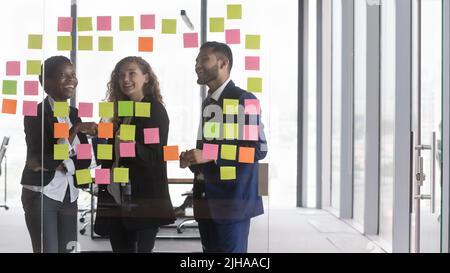 Glückliches, vielfältiges Treffen des tausendjährigen Geschäftsteams an Bord mit Notizen Stockfoto