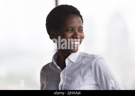 Glückliche fröhliche afroamerikanische Geschäftsführerin Frau, die wegschaut Stockfoto